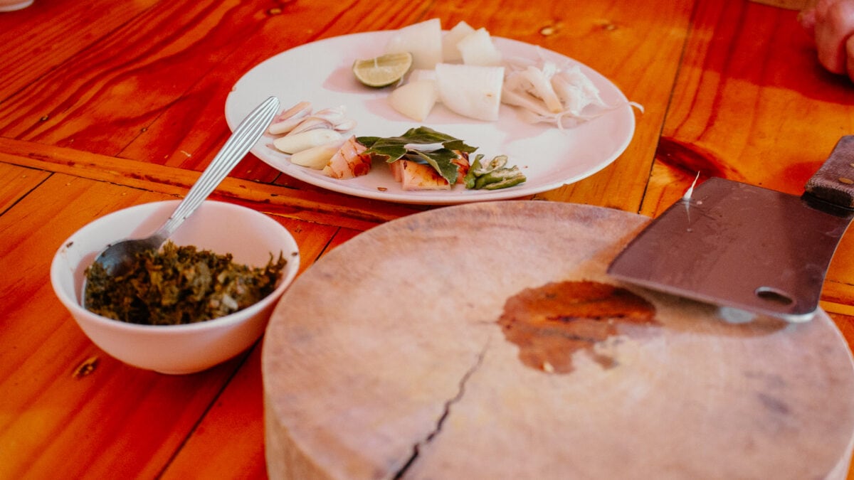 Teller mit frischem Essen, Hackmesser und Holzbrett.