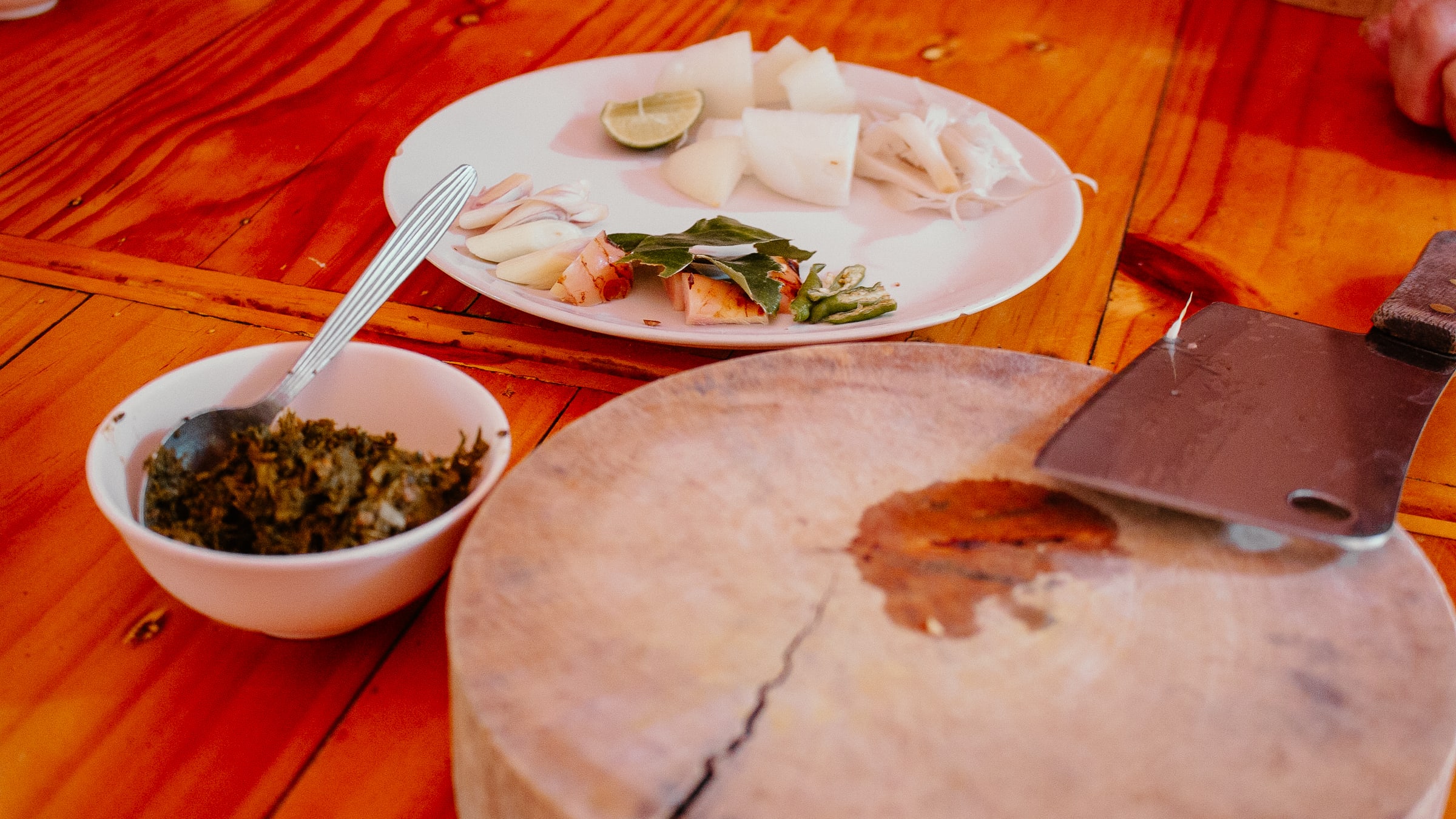 Teller mit frischem Essen, Hackmesser und Holzbrett.