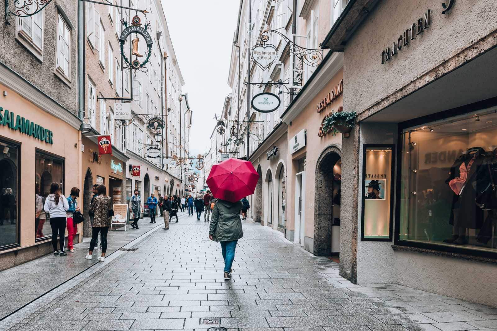 Frau mit Schirm bei Schnürlregen in der Getreidegasse in der Altstadt von Salzburg