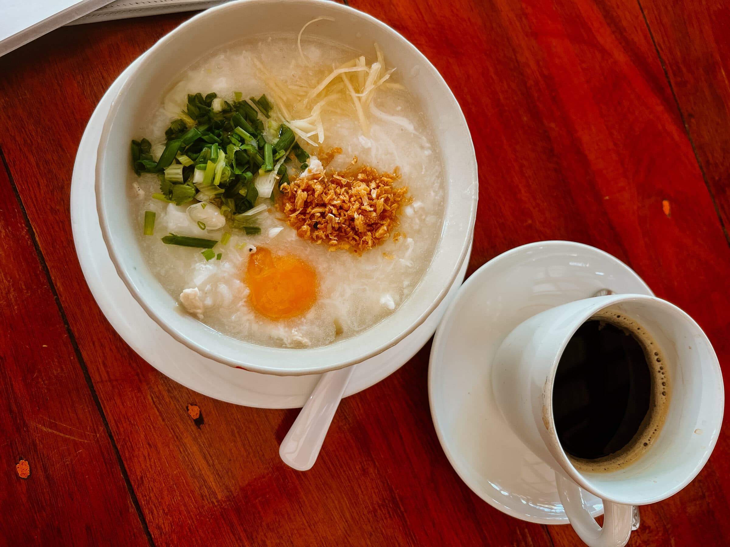 Thai rice soup Khao Tom for breakfast with egg, fresh herbs and ginger