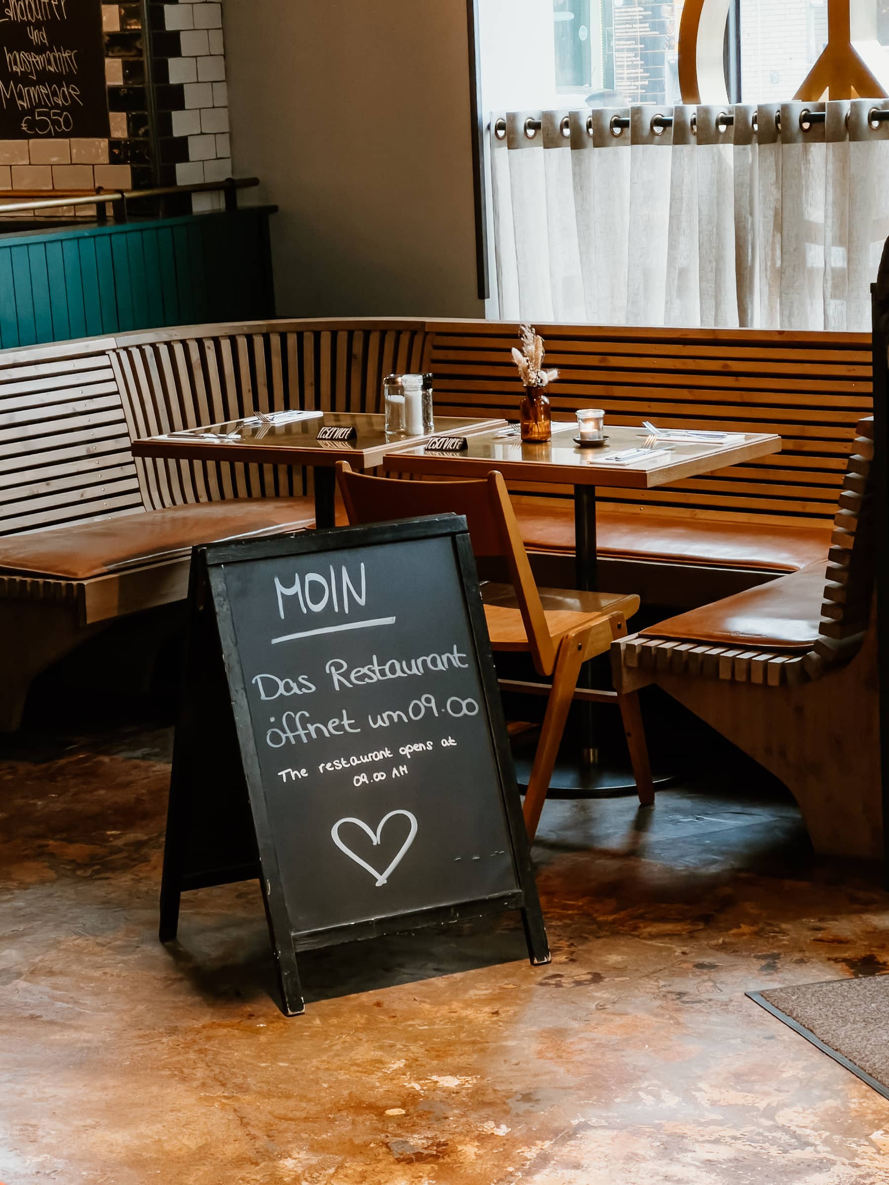 Schild mit Öffnungszeiten im Restaurant im Mutterland Stammhaus in Hamburg
