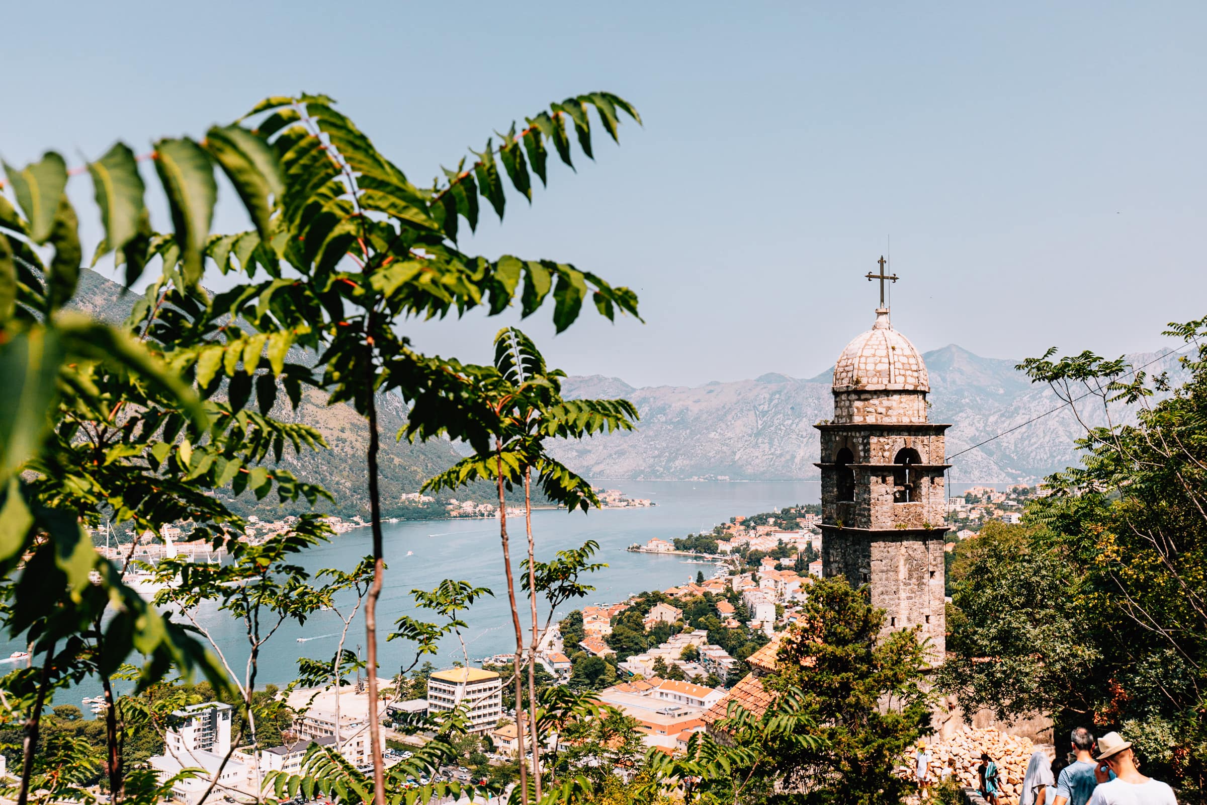 Kirchturm mit Blick auf Küstenstadt und Berge.