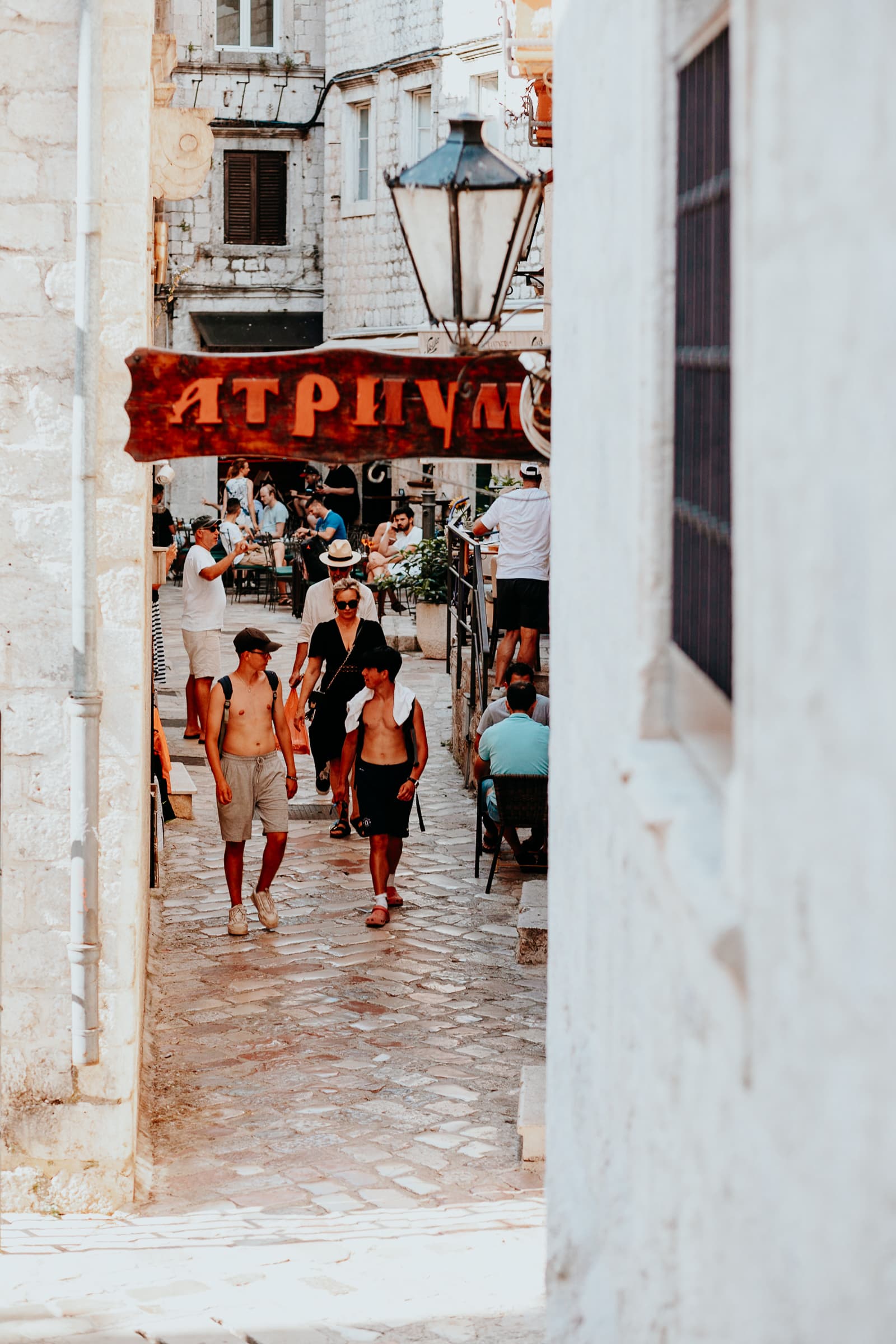 Menschen in einer engen Gasse mit Cafés.