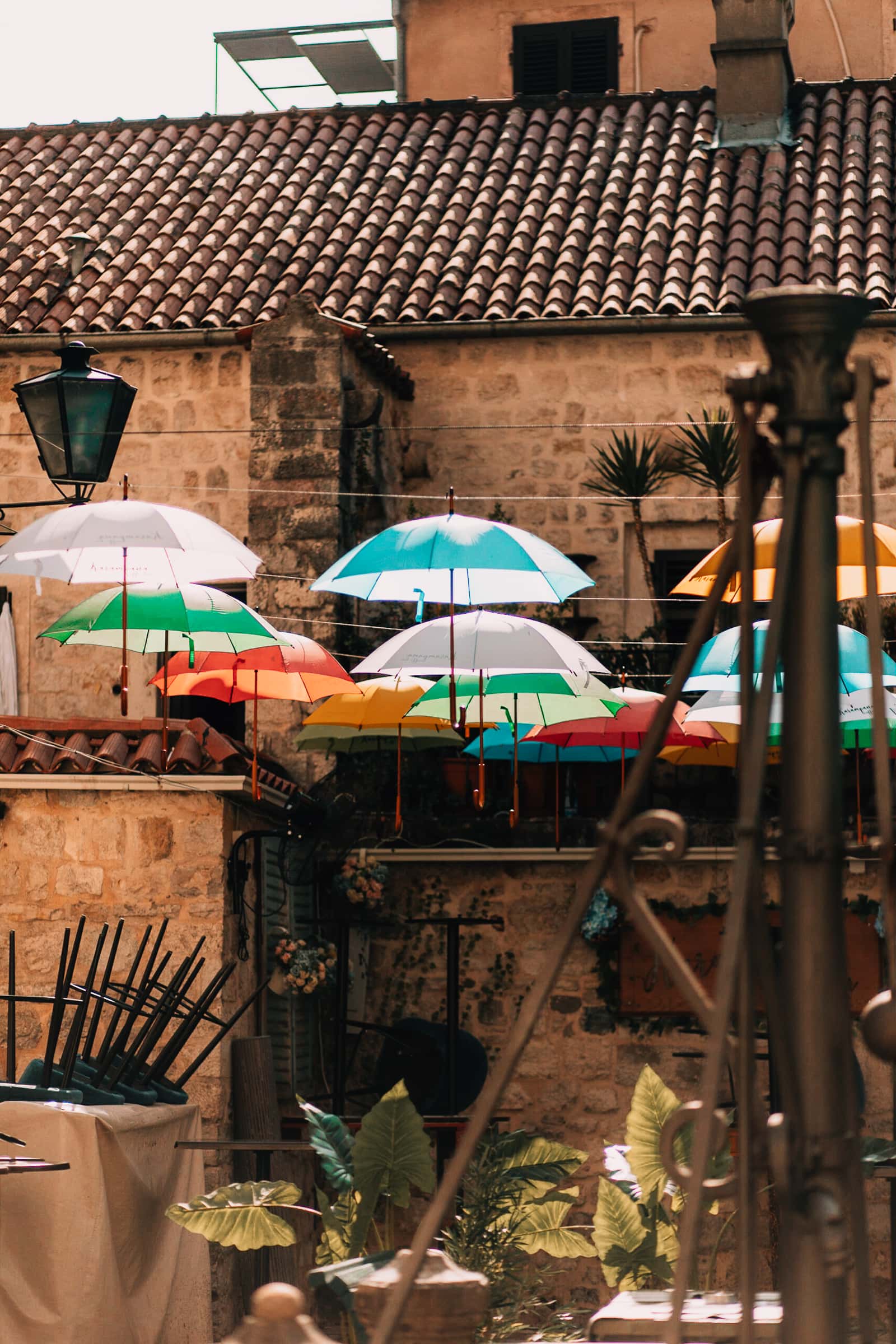 Bunte Regenschirme schmücken mediterrane Gasse.