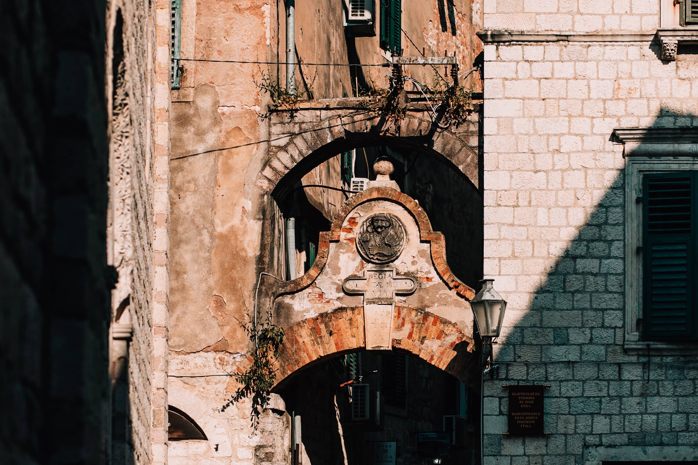 Altes Steinportal mit Wappen in Sonnenlicht.