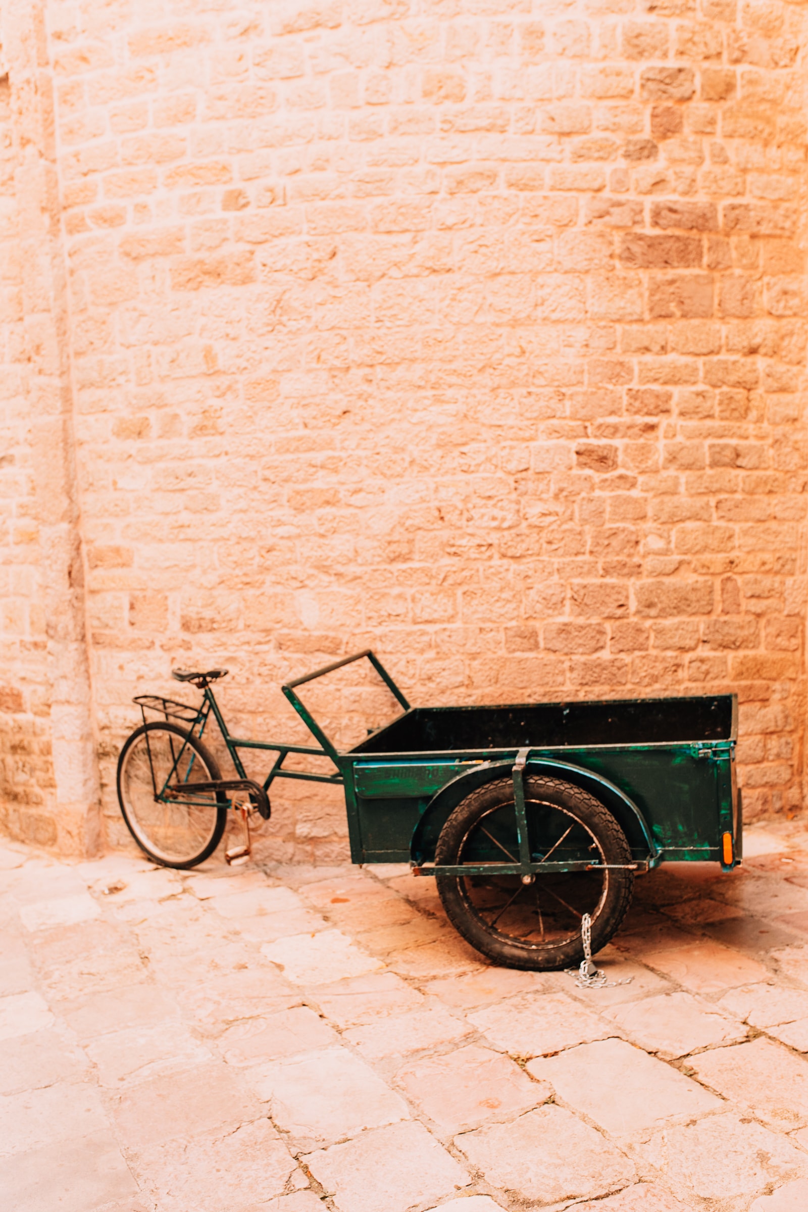 Grünes Lastenfahrrad an Steinmauer.