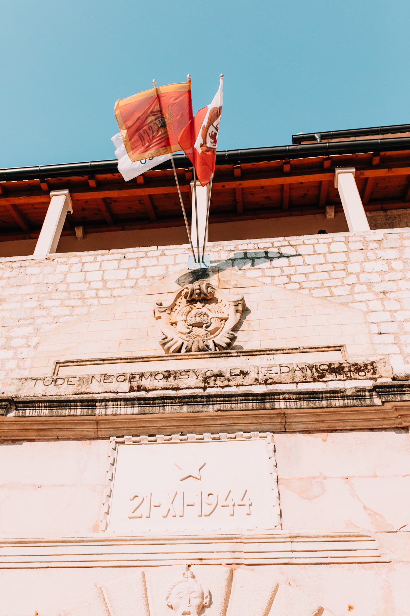 Montenegrinische Flaggen und Gedenktafel an Fassade in Kotor