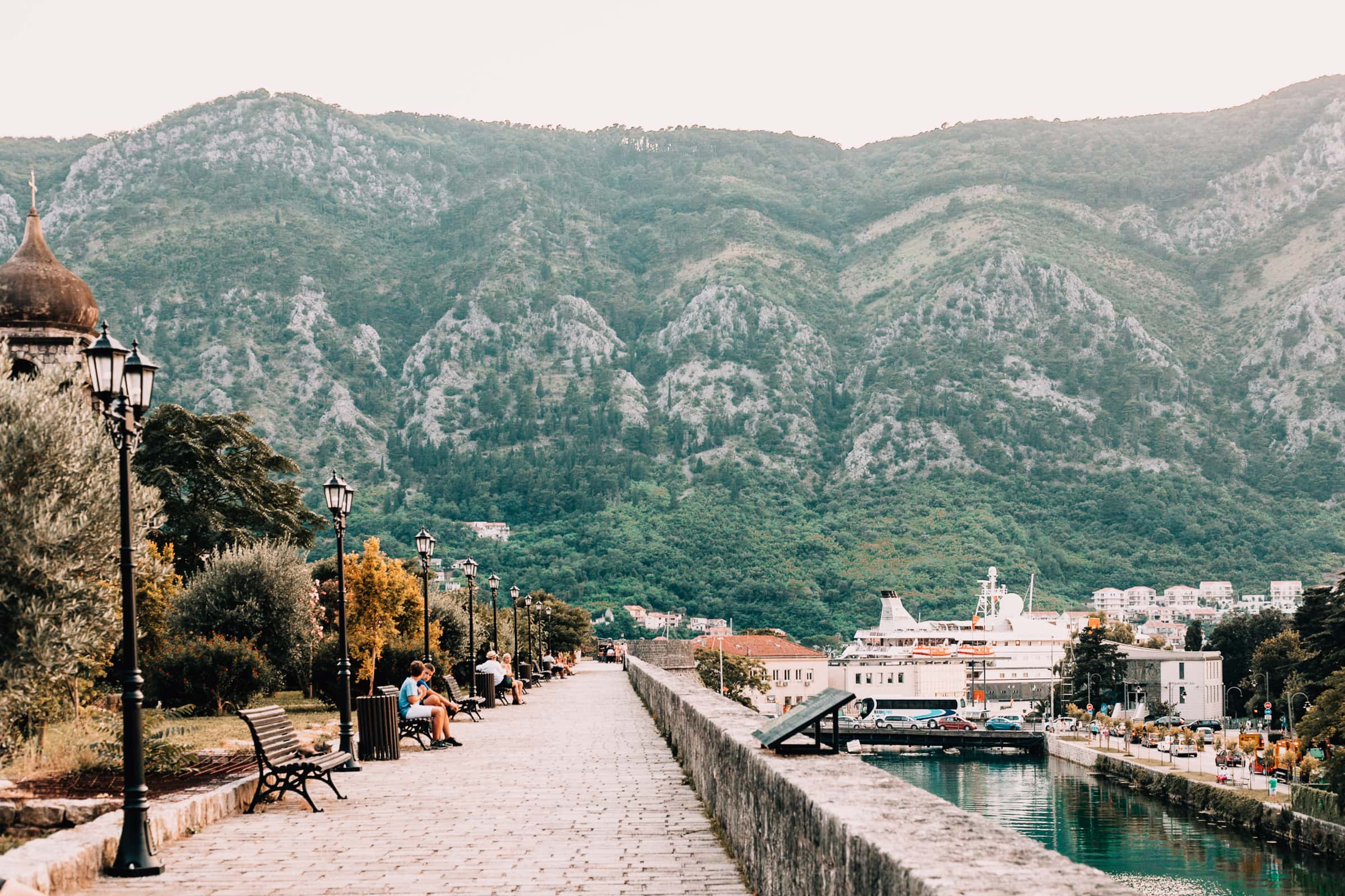 Uferpromenade mit Bergen und Parkbänken.