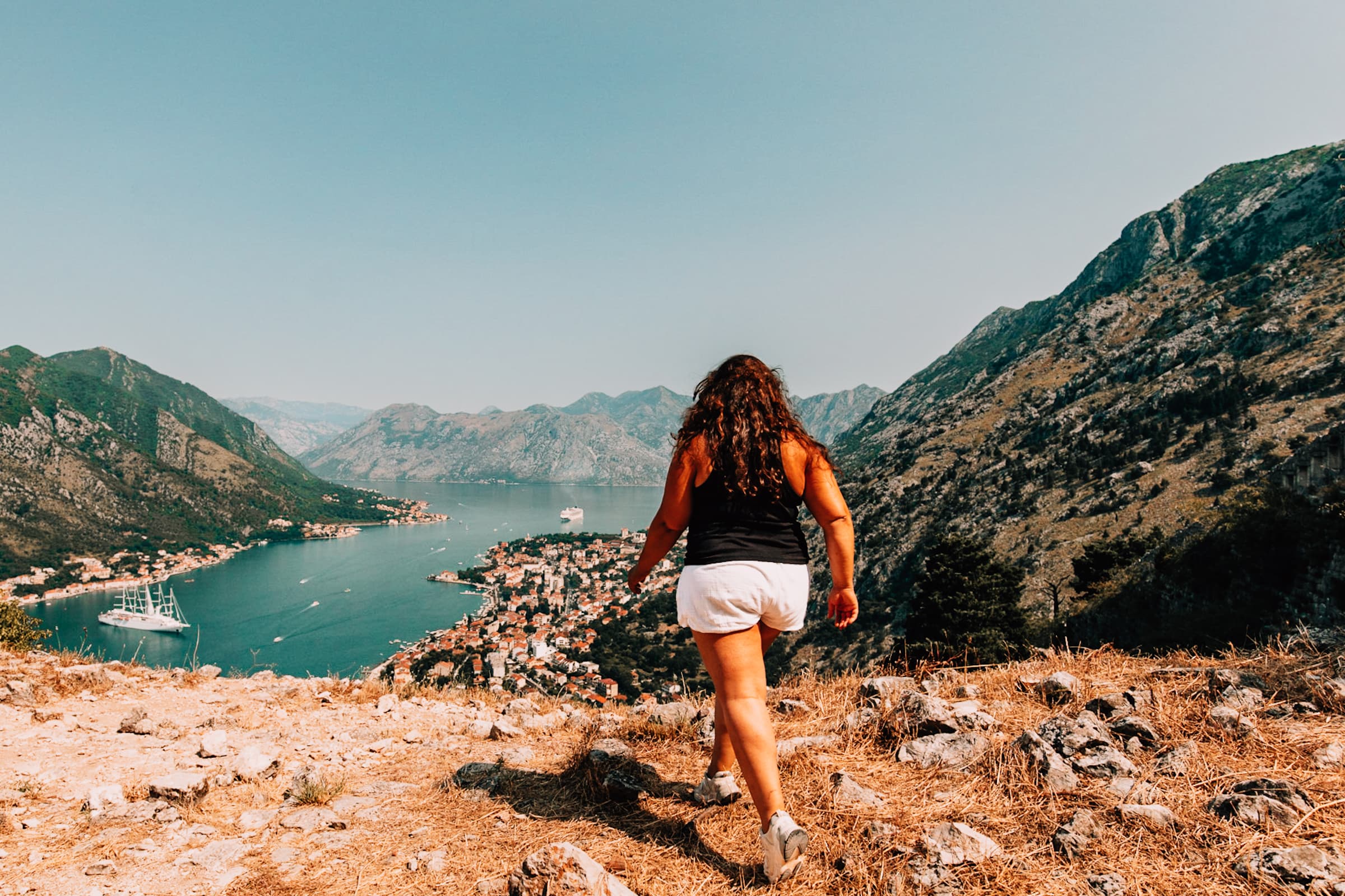 Frau wandert auf Berg mit Blick auf Küstenstadt.