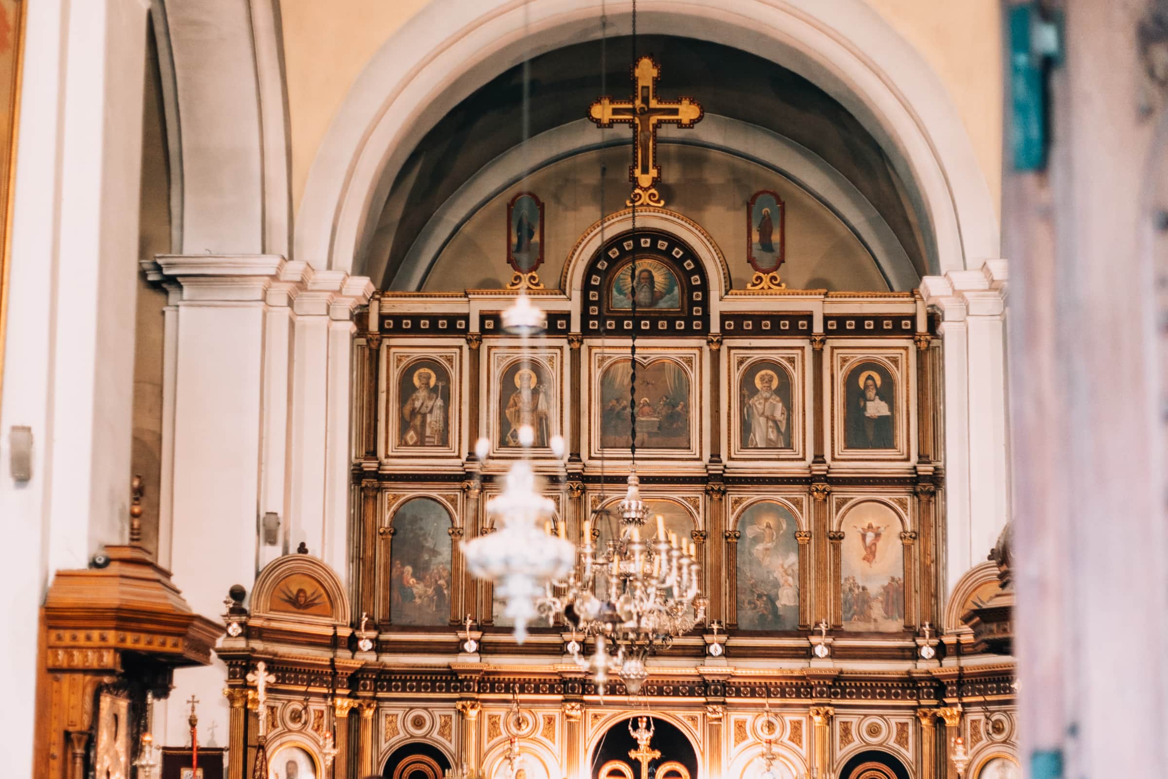 Innenansicht einer Kirche mit Ikonostase und Kerzenleuchter.