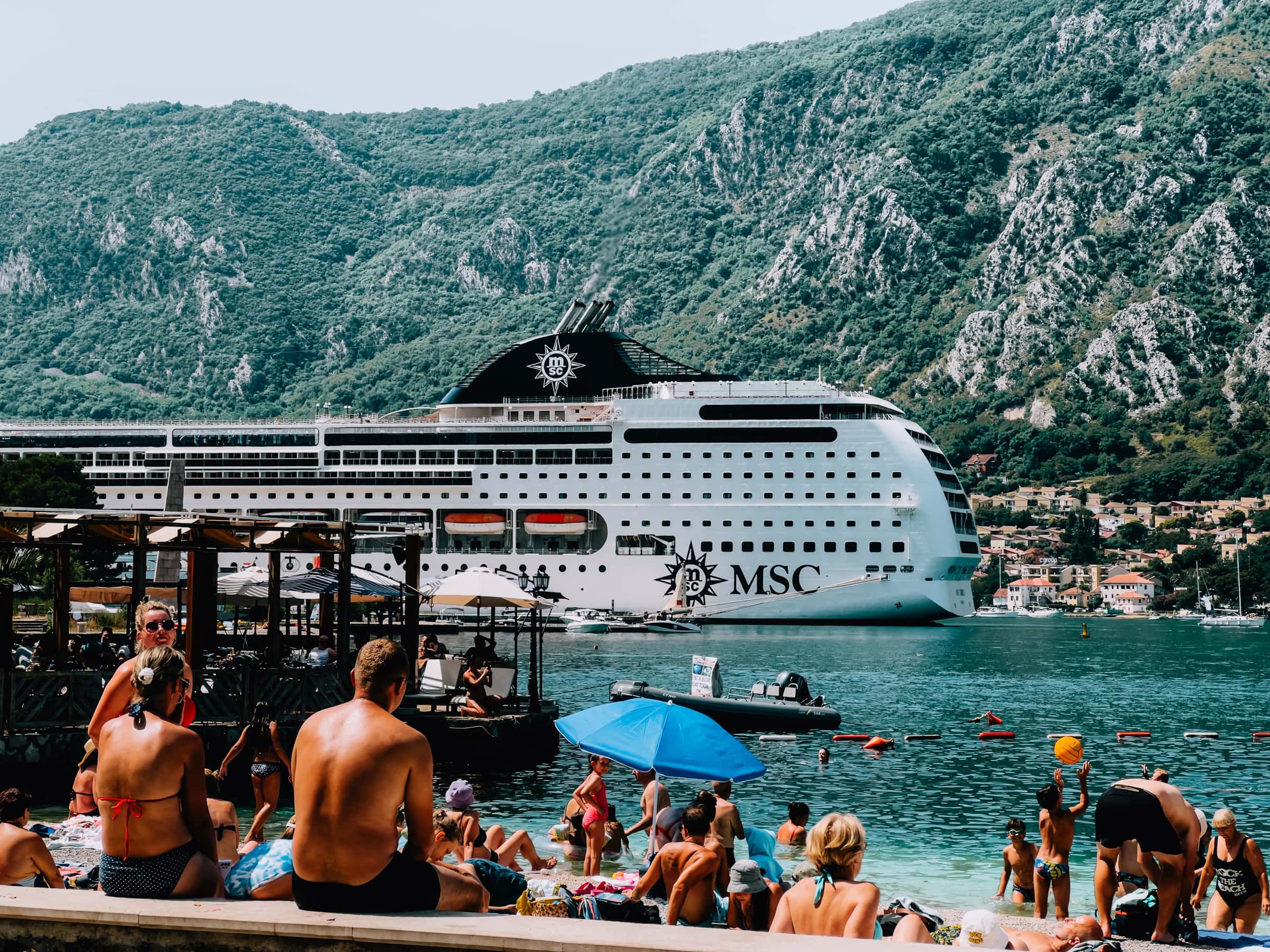 Kreuzfahrtschiff im Hafen, Menschen am Strand, Sommerurlaub