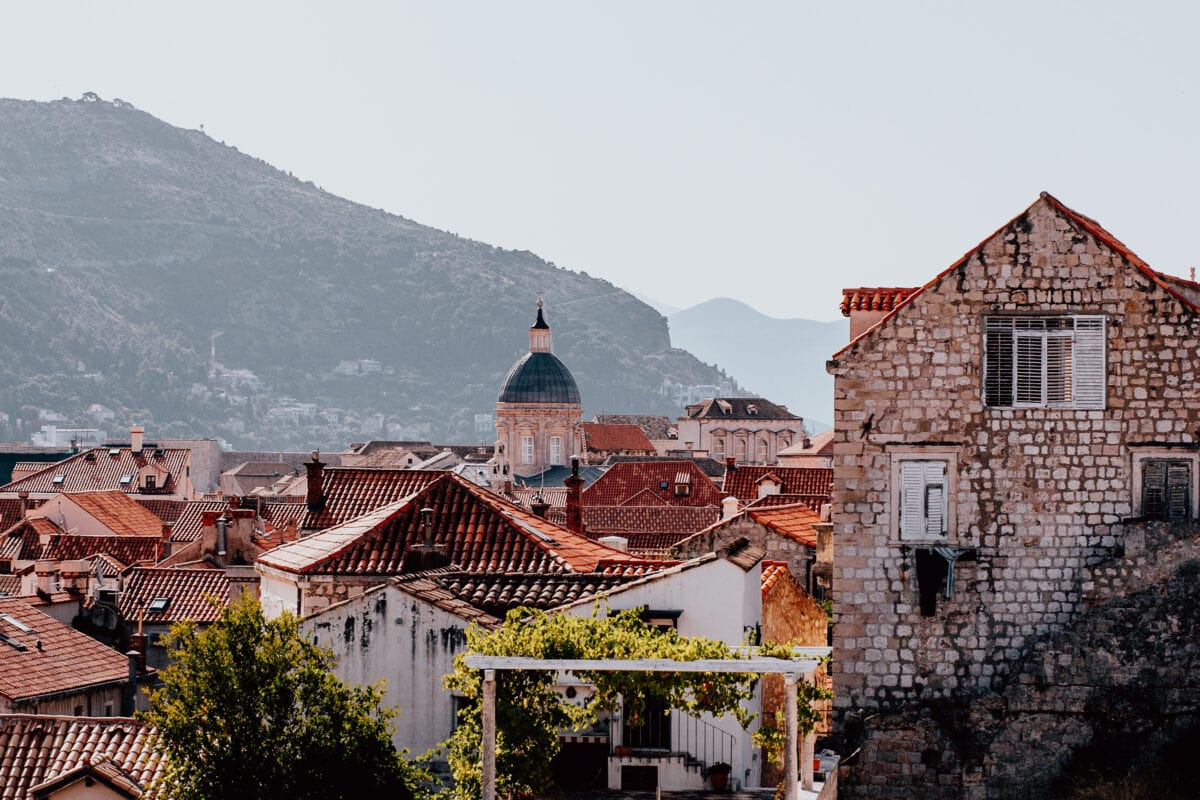 Historische Stadtansicht mit roten Dächern und Kuppel.