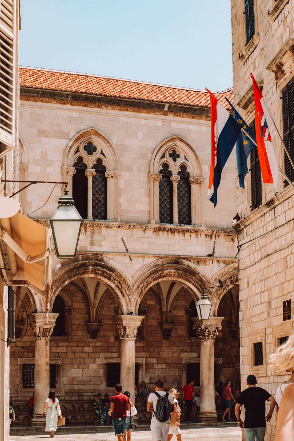 Historisches Gebäude mit Flaggen und Touristen.