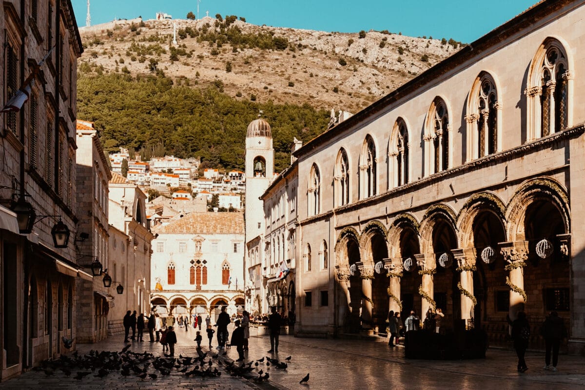 Historische Altstadtgasse mit Menschen und Tauben.
