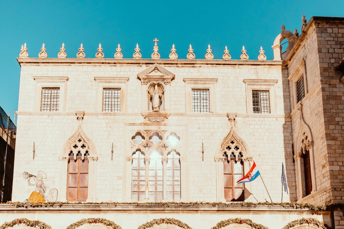 Historisches Gebäude mit gotischen Fenstern und Flaggen.