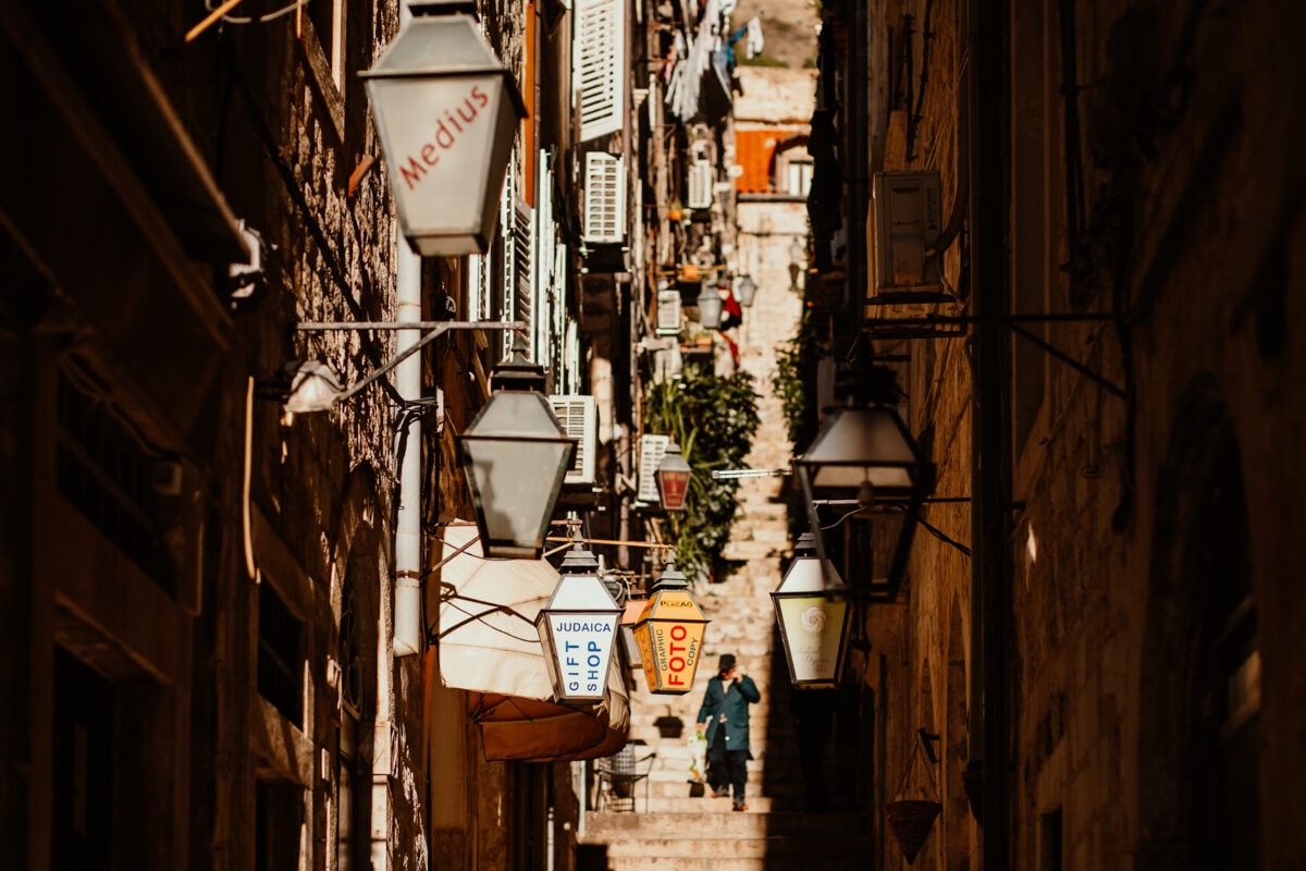 Enge Gasse mit Laternen und Person.