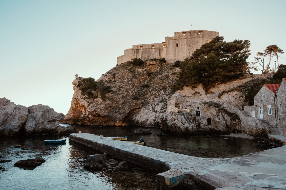 Festung auf Klippe über kleinem Hafen bei Sonnenuntergang