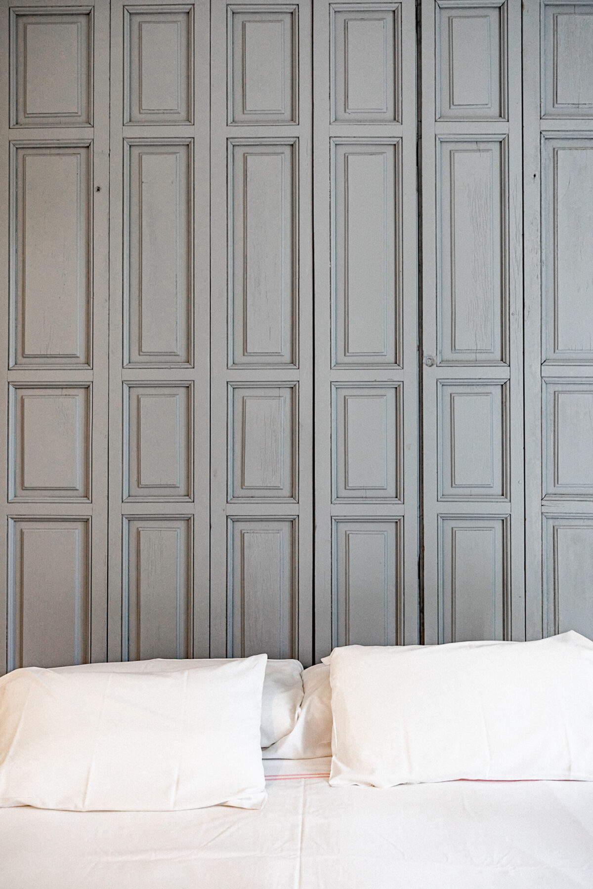 Gemütliches Bett vor alten Holztüren.