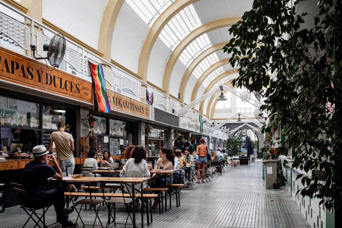 Markthalle mit Essensständen und sitzenden Menschen.