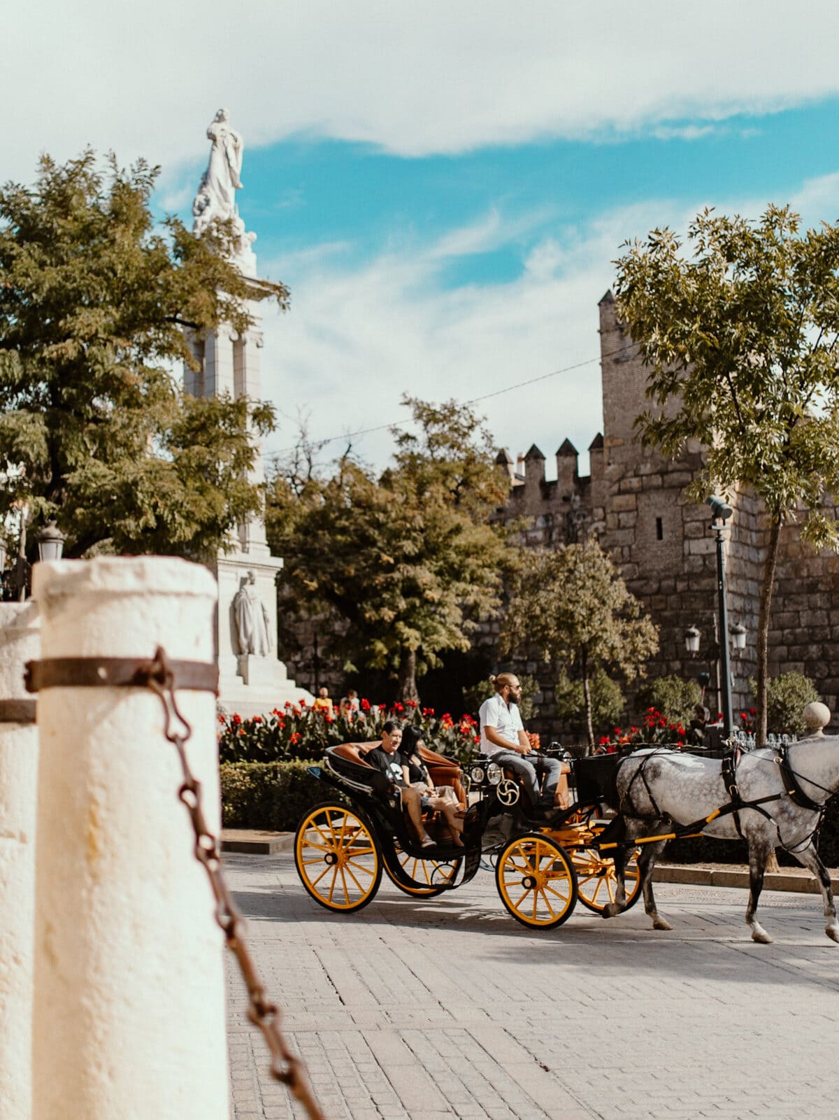 Kutsche mit Pferden vor historischem Denkmal.
