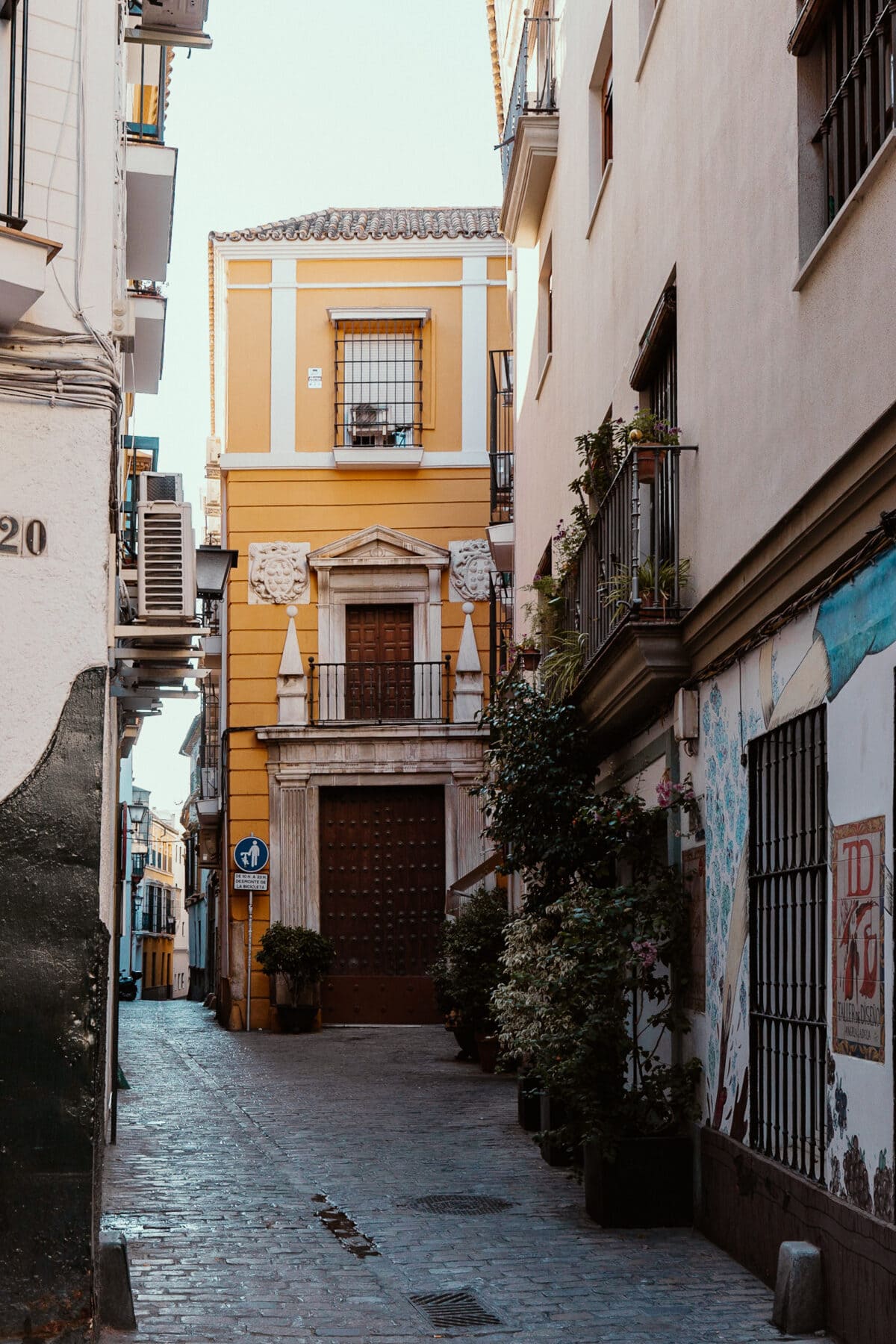 Enggasse in spanischer Altstadt mit gelbem Gebäude.