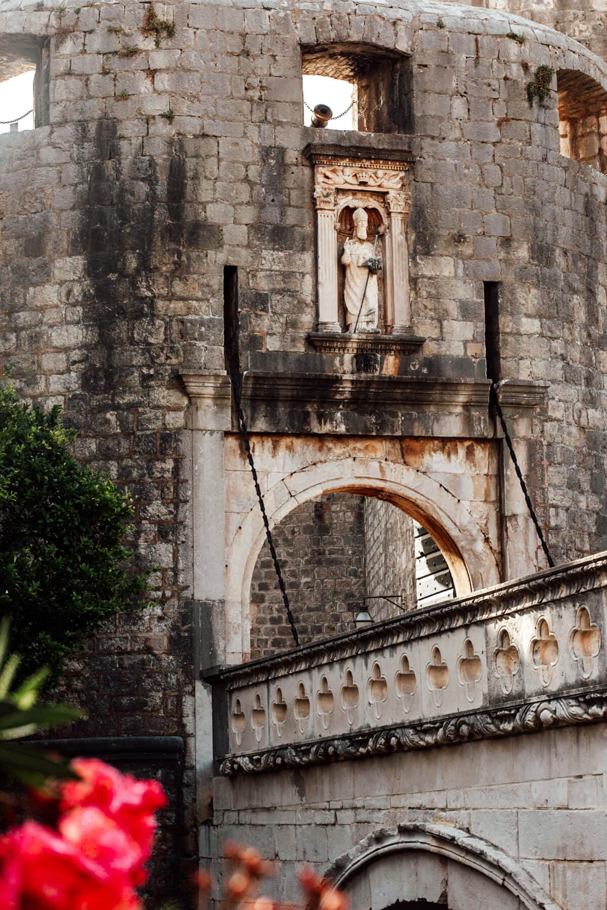 Historische Steinarchitektur mit Statue und Blumen.