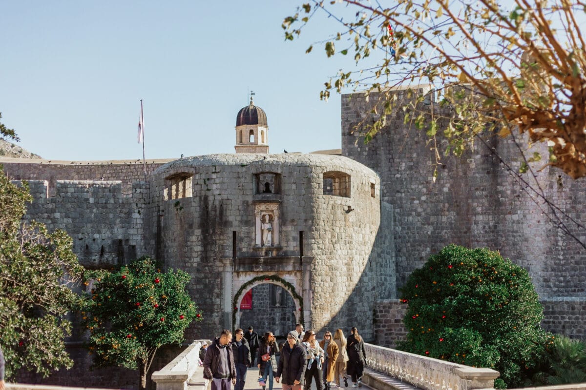 Touristen vor historischer Festungsmauer mit Torbogen.