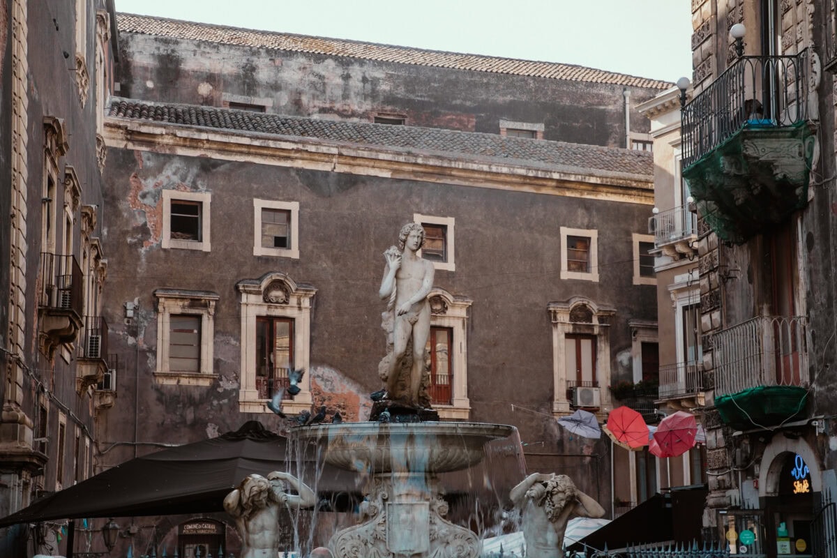 Statue an Brunnen vor historischem Gebäude.