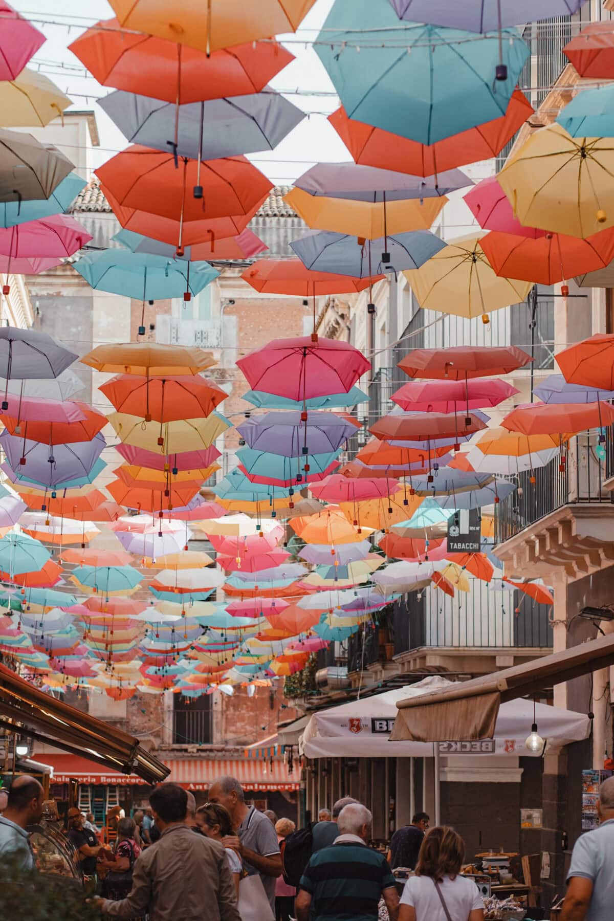 Bunte Schirme schweben über belebter Straße.