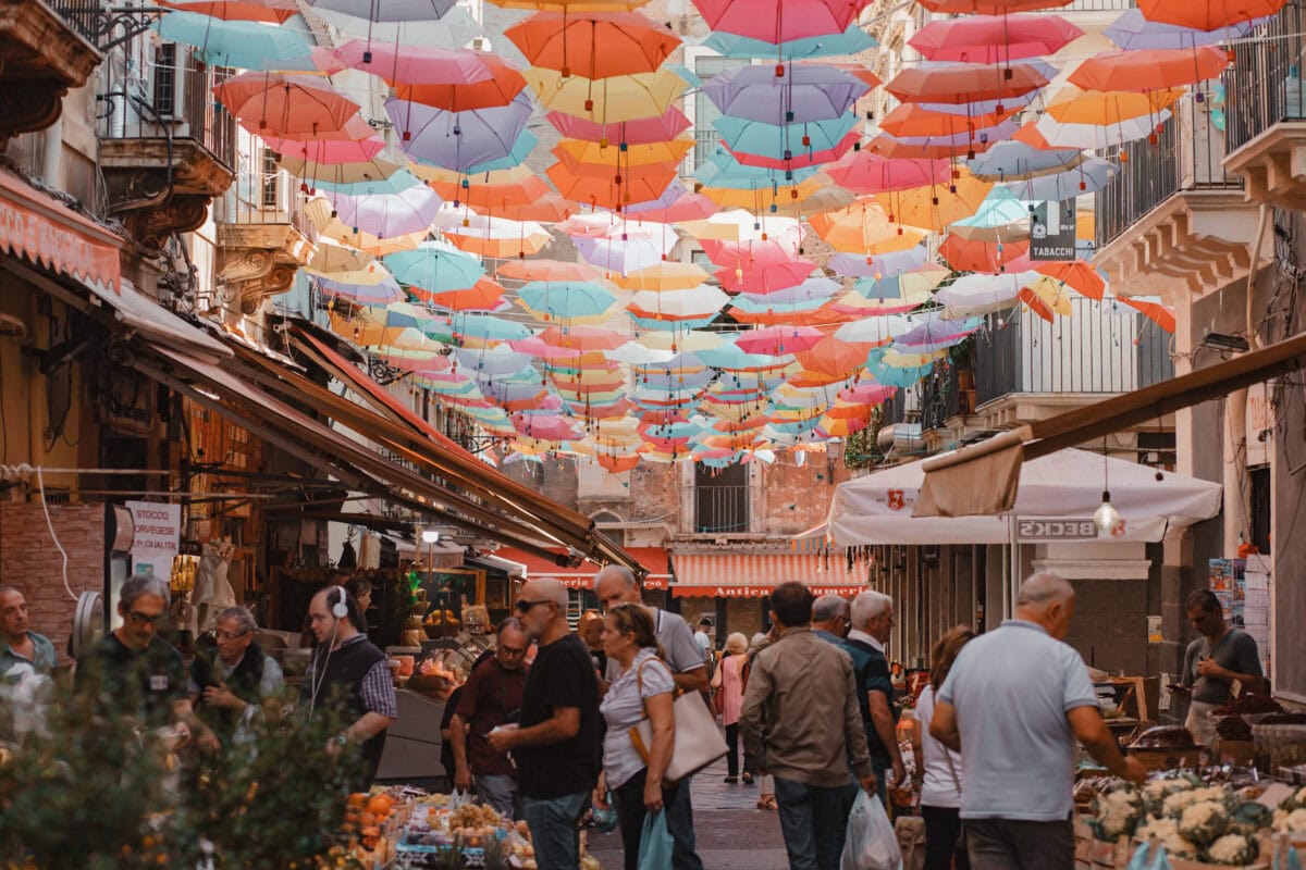 Bunte Schirme über belebtem Marktplatz.
