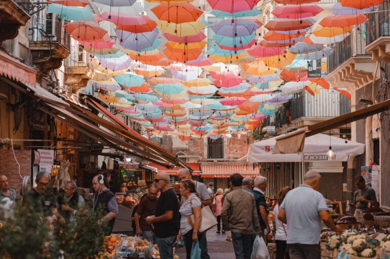 Bunte Schirme über belebtem Marktplatz.