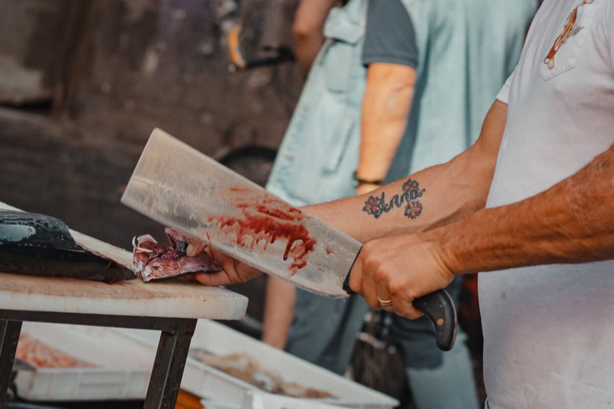 Metzger schneidet Fleisch auf Marktstand.