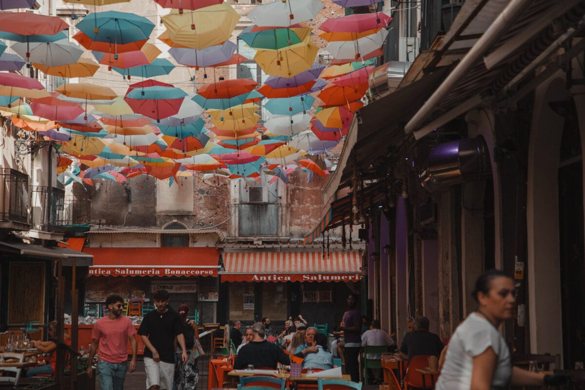 Bunte Schirme schweben über belebter Straße.