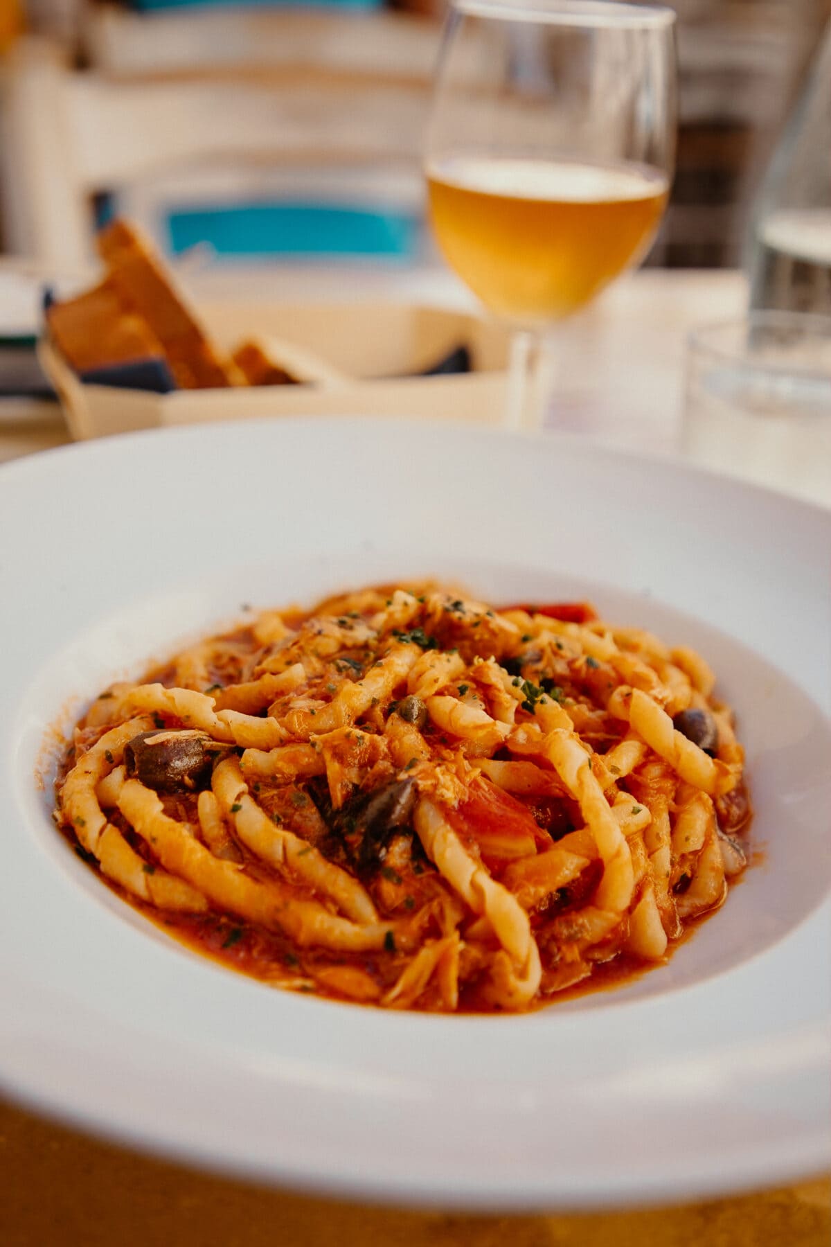 Teller mit Pasta und Glas Weißwein.