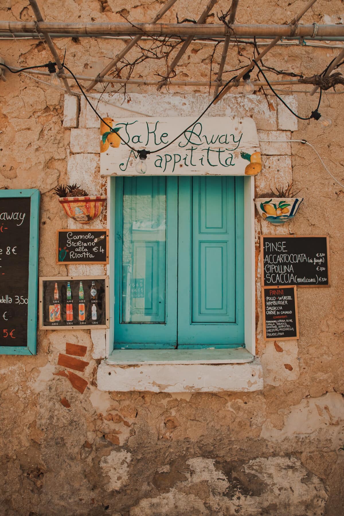 Türkisfarbene Tür und Menütafeln eines kleinen Restaurants.