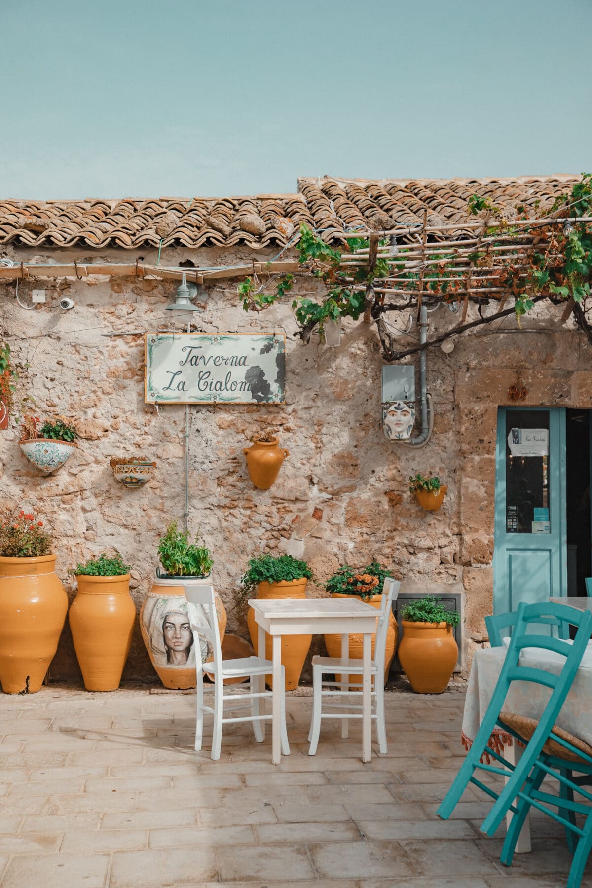 Gemütliche Taverne im Freien mit Töpfen und Pflanzen.