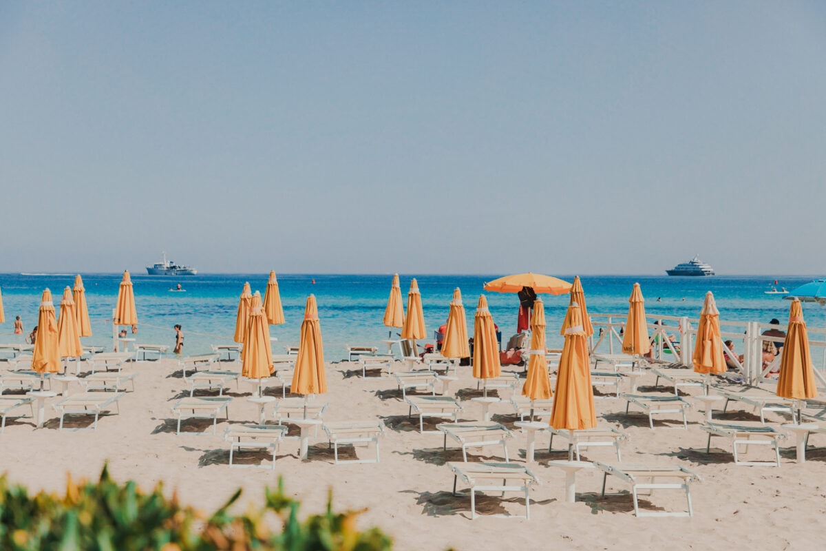 Strand mit orangefarbenen Sonnenschirmen und Meerblick.
