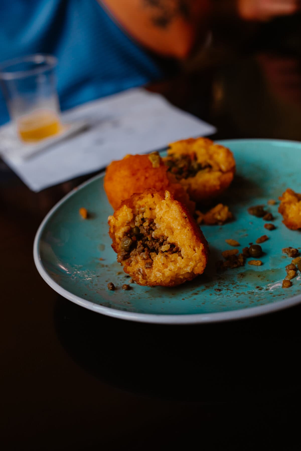 Angebrochener gefüllter Arancini auf blauem Teller.