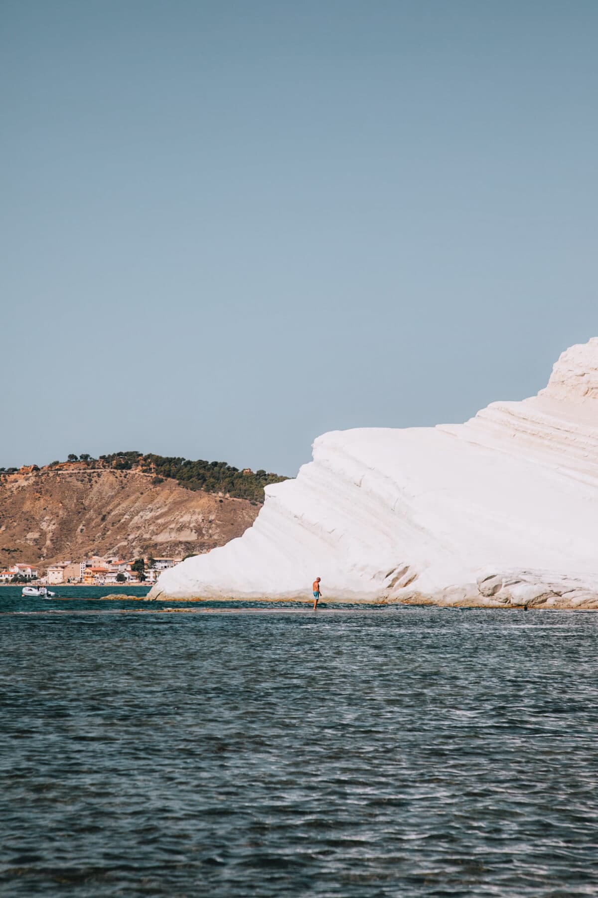 Person steht auf weißen Felsen am Meer