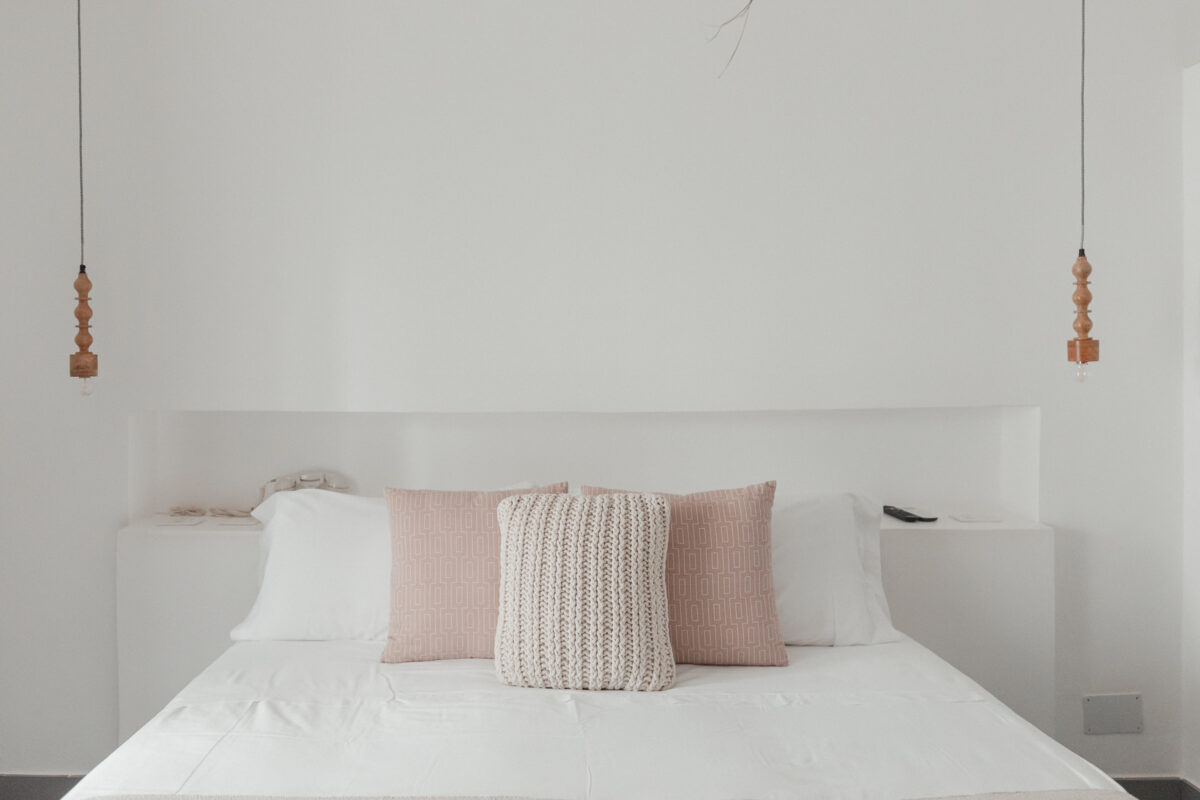 Minimalistisches Schlafzimmer mit weißen und rosafarbenen Kissen.