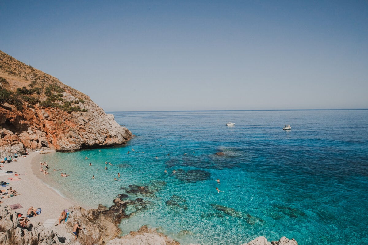 Klare blaue Bucht mit Strandbesuchern und Booten.