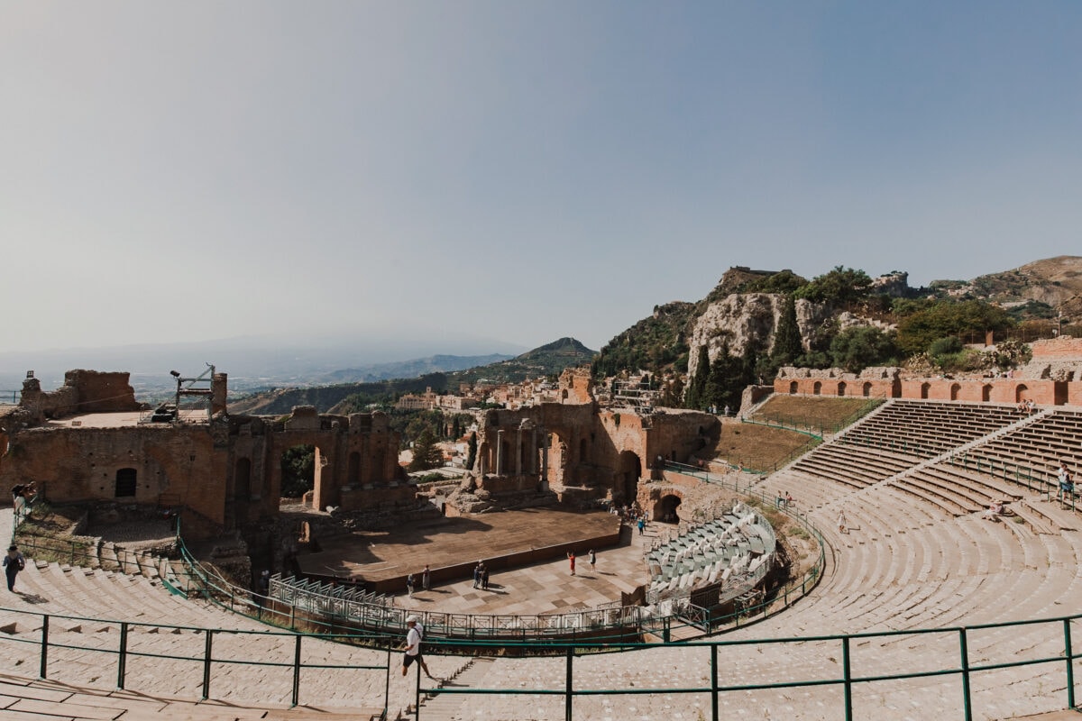 Antikes Theater in hügeliger Landschaft.