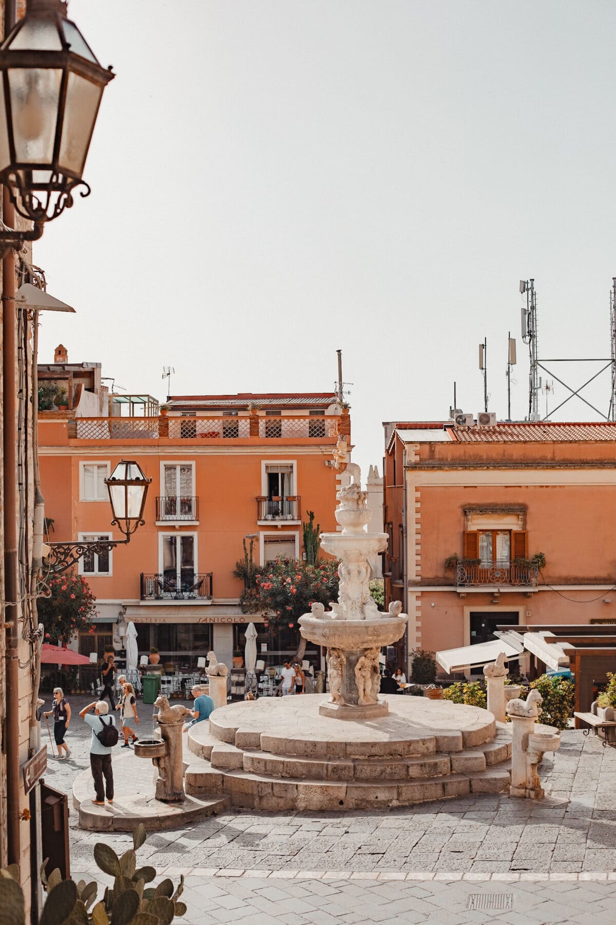 Italienischer Platz mit Brunnen und Passanten.