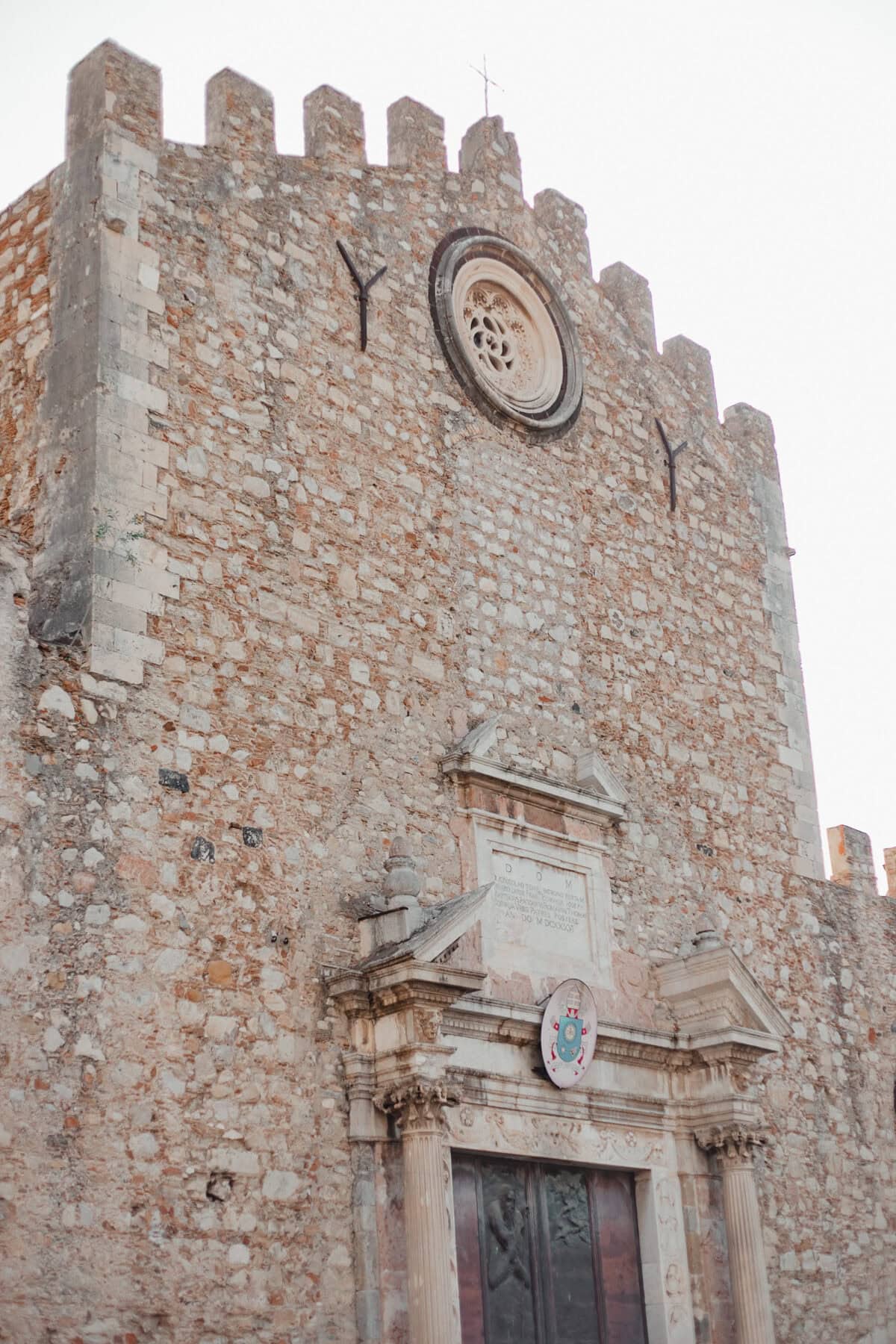 Alte Steinfassade einer Kirche mit Rundfenster.