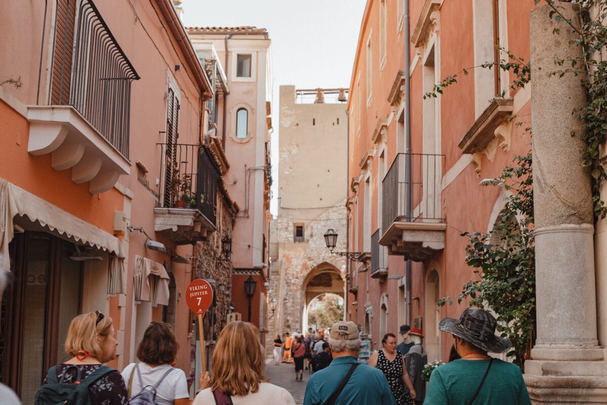 Alt-Text: Besucher in einer historischen Gasse mit pastellfarbenen Häusern.