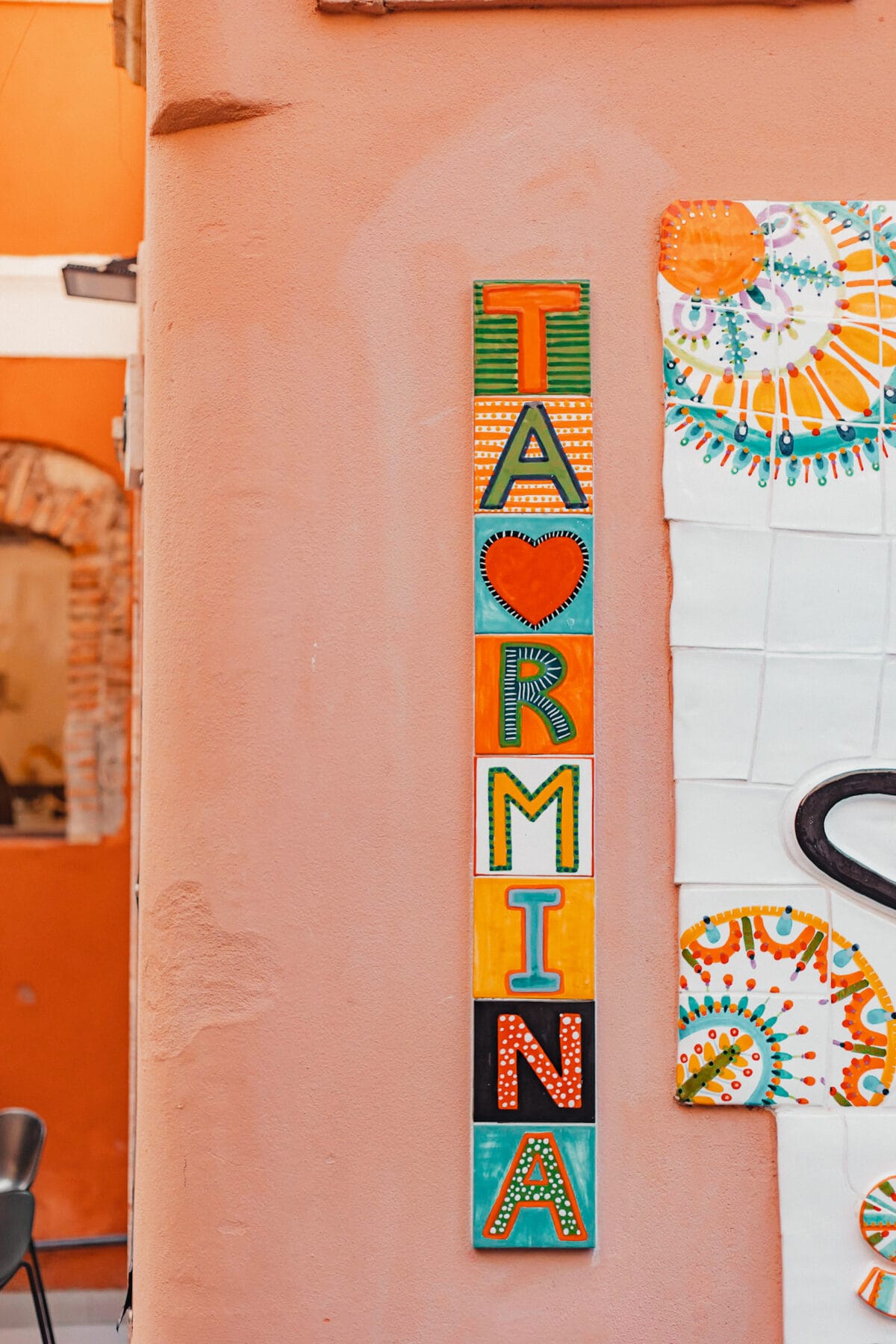 Buntes Keramikschild "Taormina" an Wand.