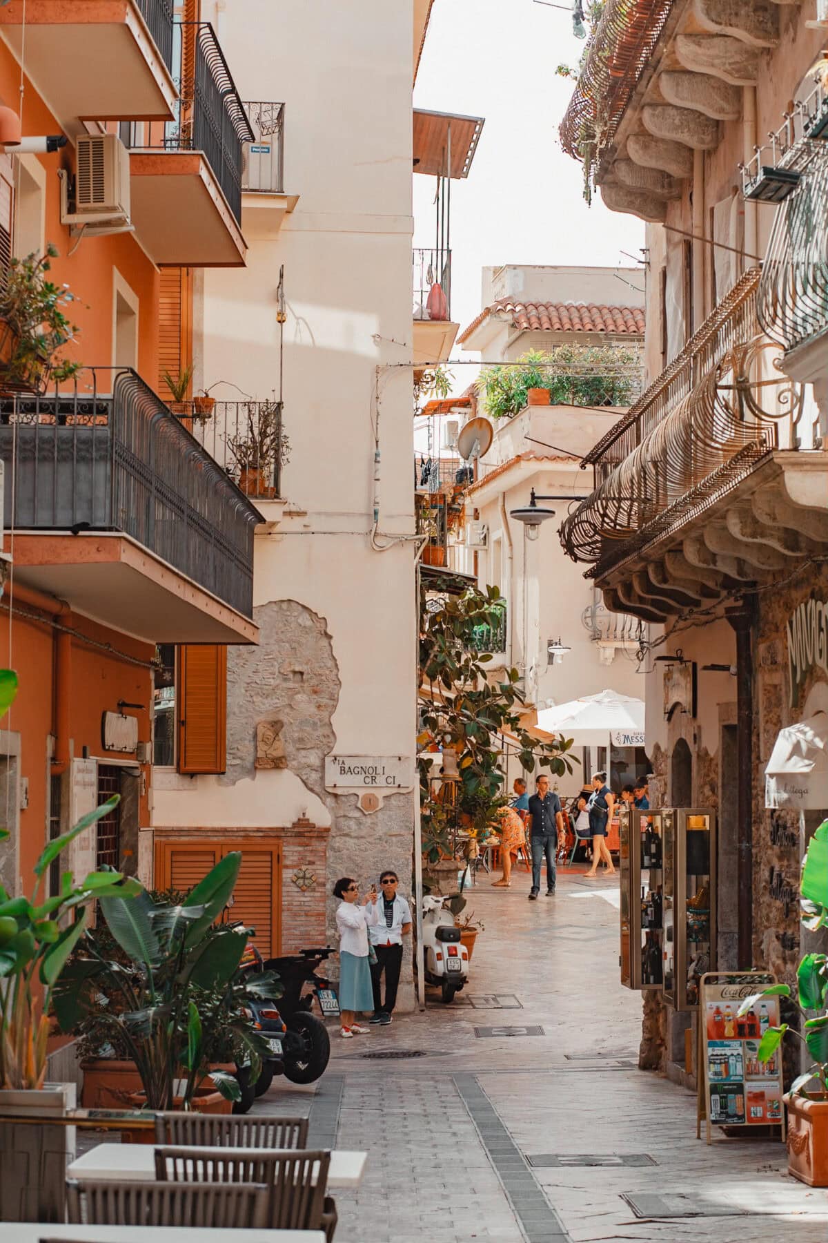 Sizilianische Straße mit Passanten und Roller.