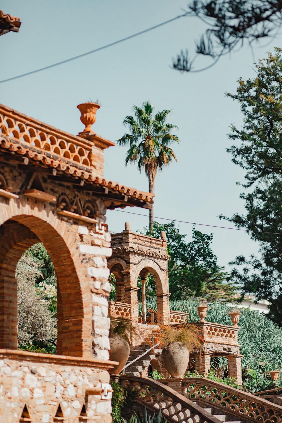 Mediterraner Garten mit Bogenstruktur und Palmen.