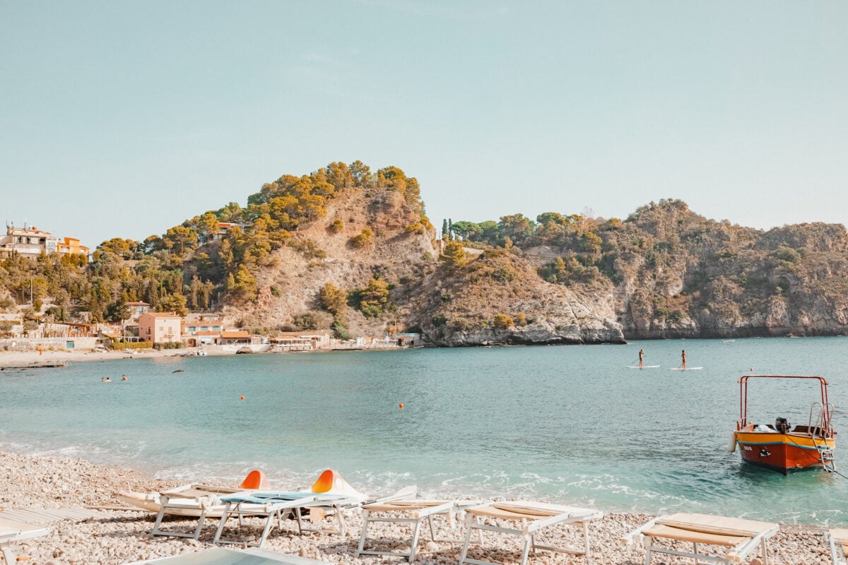 Mittelmeerstrand mit Boot und Paddlern.