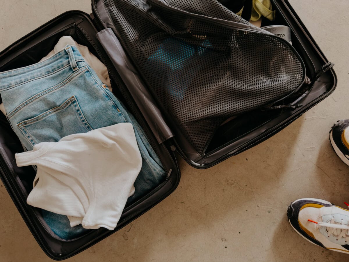 Geöffneter Koffer von Horizn Studios mit Kleidung und Schuhen.